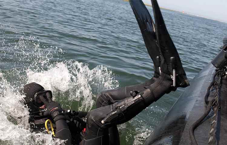Why do Scuba Divers Dive/Fall Backwards off Boats into the Sea?